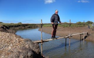 The National Trust has submitted plans to rebuild a bridge over Stiffkey marshes which it removed more than two years ago. Pictured is Stiffkey resident Ian Curtis on a makeshift bridge over the creek