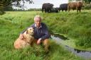 Farmer Robert Perowne and his dog, Lupin, by the River Stiffkey on his land where sewage ran from a burst pipe
