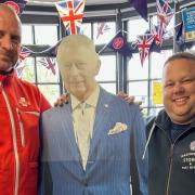 Great Massingham postmaster Mark Eldridge (right) posing with Lee Nicol, and a cardboard cutout of King Charles as the post office prepares to celebrate the coronation